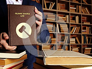 ISLAMIC SHARIA LAW book in the hands of a jurist. Sharia lawÂ isÂ Islam`sÂ legal system. It is derived from bothÂ theÂ Koran